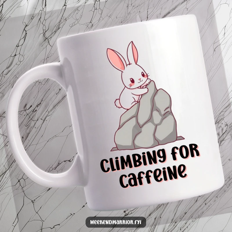 Funny kawaii rabbit with determined paws scaling a miniature rock face, printed on a mug. A humorous and inspiring design for climbers.